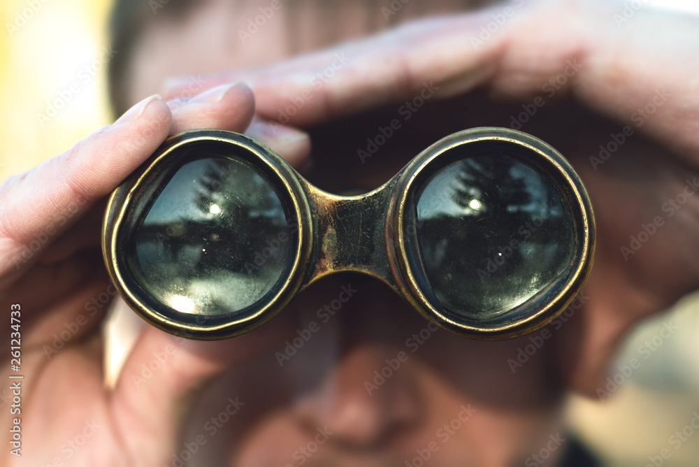 Man is looking through a binoculars close up.