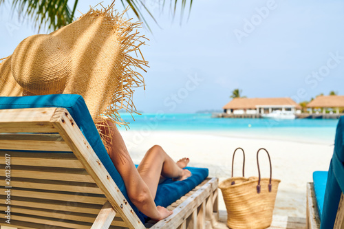 Fototapet Woman at beach on wooden sun bed loungers