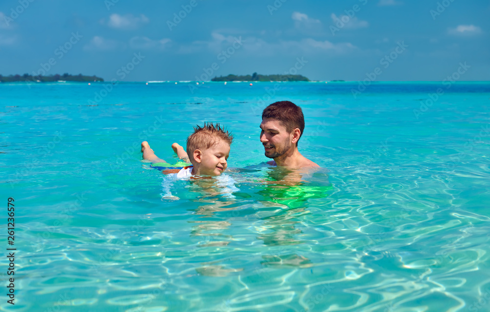 Toddler boy learns to swim with father