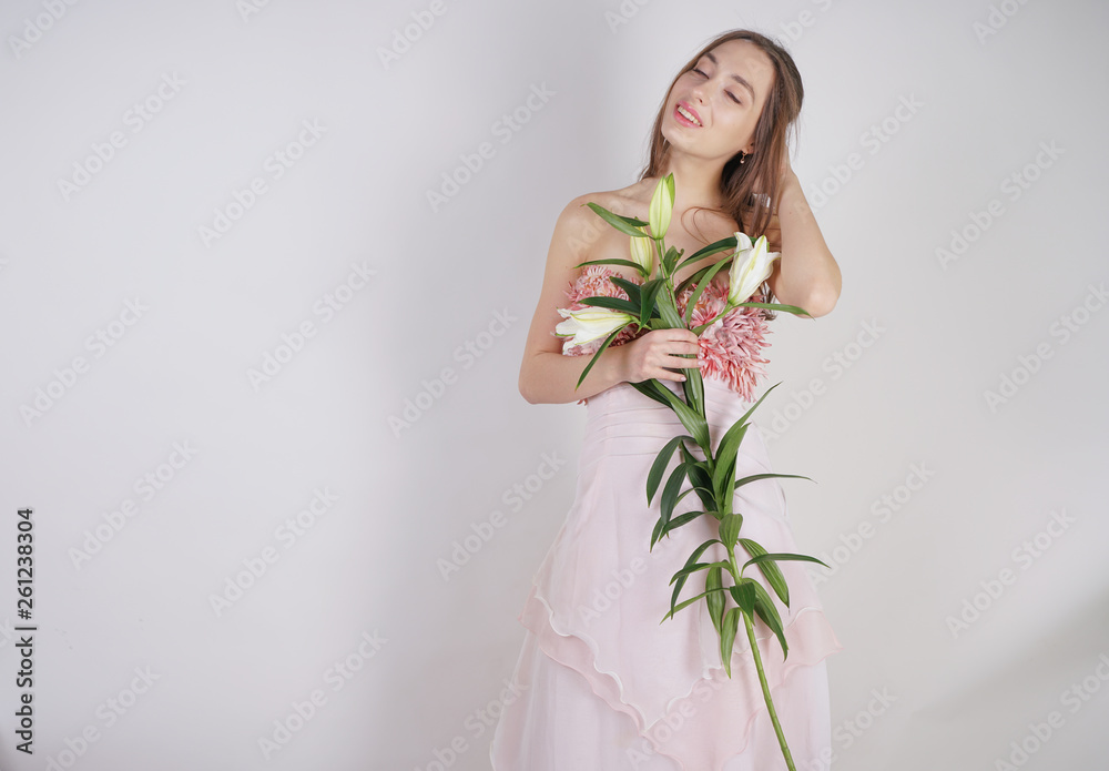 charming young caucasian girl in a pretty dress holds a lush Lily flower in her hands and stands on a white background in the Studio alone charming young caucasian girl in a pretty dress holds a lush Lily flower in her hands and stands on a white background in the Studio alone