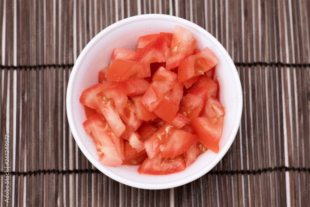 Sliced tomatoes in a bowl on the table. View from above.