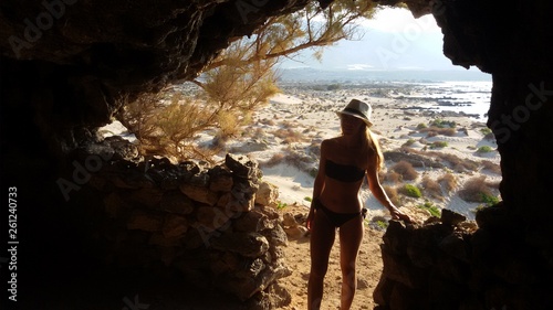 a beautiful girl in a bikini at the opening of a cave overlooking the beautiful beaches of the island of Elafonisi on Crete in Greece
