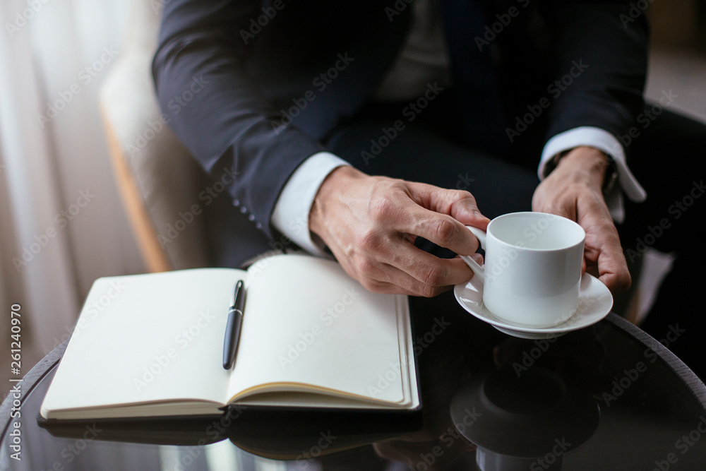 Businessman taking notes while having coffee. Businessman taking notes while having coffee.
