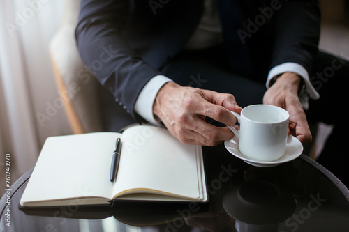 Businessman taking notes while having coffee.