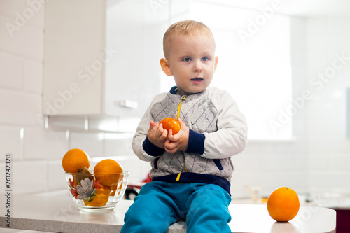 Cute toddler with fruits in kitchen. Kids healthy eating concept