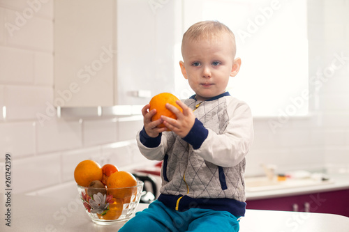 Cute toddler with fruits in kitchen. Kids healthy eating concept
