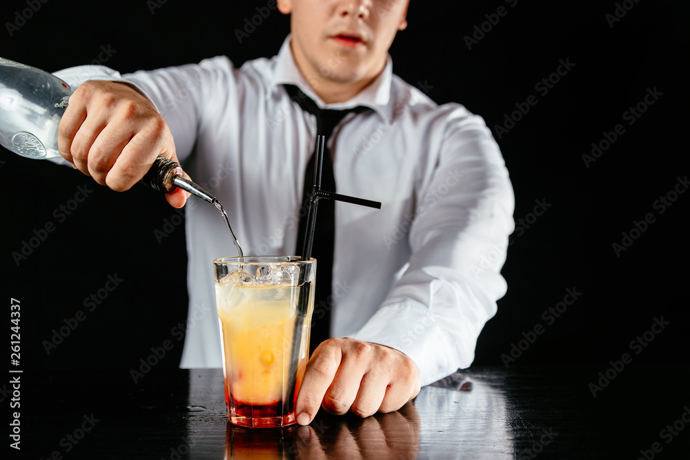 Barman makes a two colored cocktail on a black counter, black background. Barman makes a two colored cocktail on a black counter, black background.