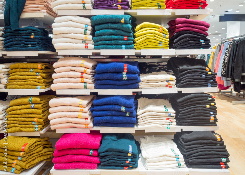 Stacks of warm sweaters different colours. A rack with clothes in a store.