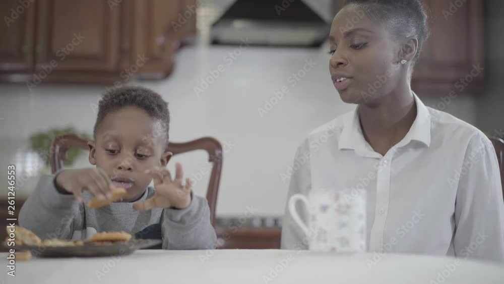 African american woman sitting with her little son by the table on the kitchen. Relationship mom and son. A happy family. Family healthy breakfast. African american woman sitting with her little son by the table on the kitchen. Relationship mom and son. A happy family. Family healthy breakfast.