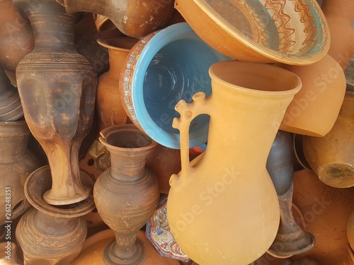 Clay pots of different color in pile, background texture.