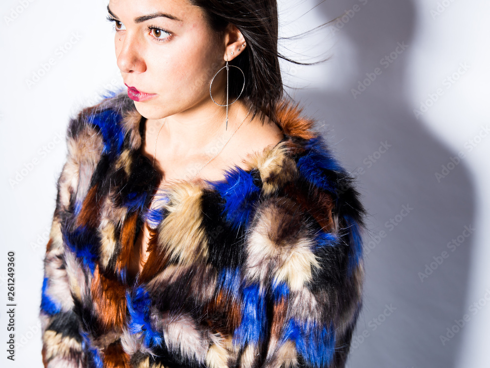 woman made up posing in a studio wearing a colorful coat woman made up posing in a studio wearing a colorful coat