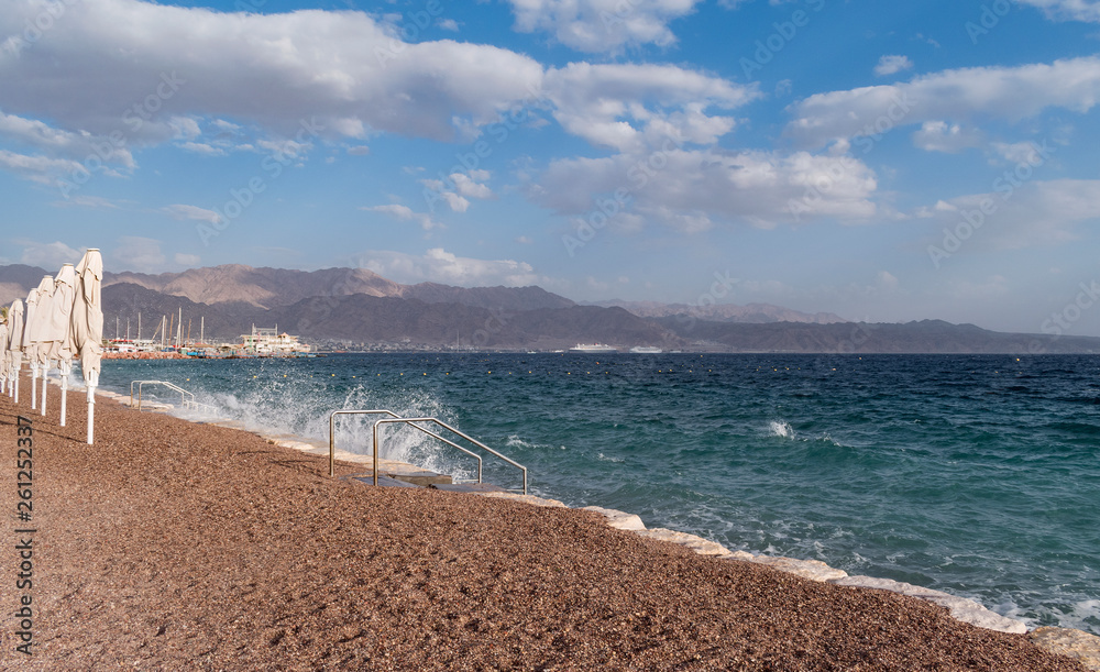 the gulf of eilat akaba on the red sea showing a resort beach with cruise ships and the mountains of jordan in the background
