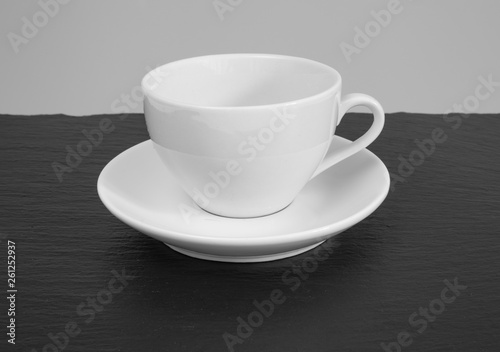 White mug and saucer on a wooden table.