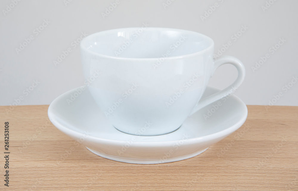 White mug and saucer on a wooden table.