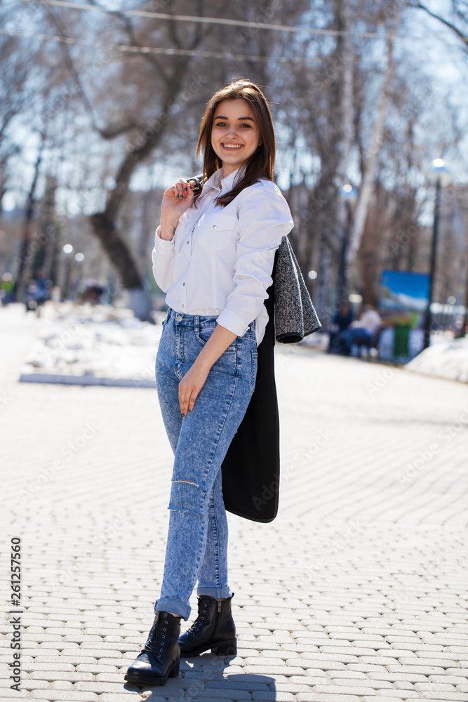 Teen girl in white shirt and blue jeans walks in spring park Stock Photo |  Adobe Stock
