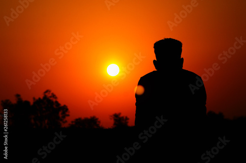 Human silhouette watching the setting sun, Satara, Maharashtra, India.