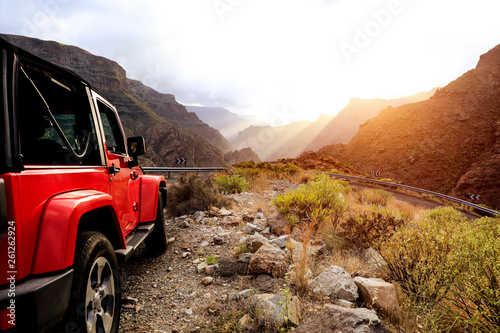 Red summer car on mountains road and summer sunset time. 
