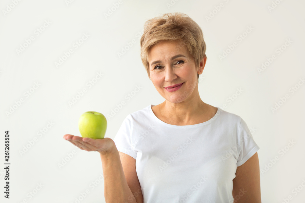 beautiful aged woman with short haircut in a white t-shirt with an apple on a white background beautiful aged woman with short haircut in a white t-shirt with an apple on a white background