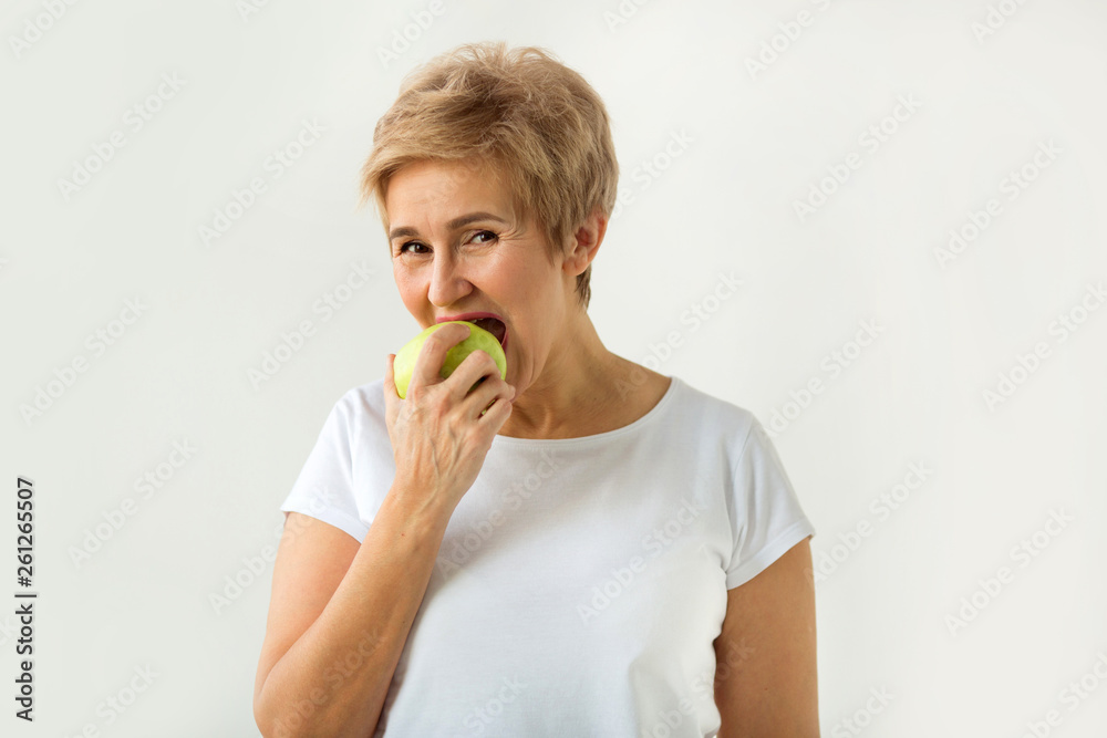 beautiful woman with a short haircut in a white t-shirt bites an apple beautiful woman with a short haircut in a white t-shirt bites an apple