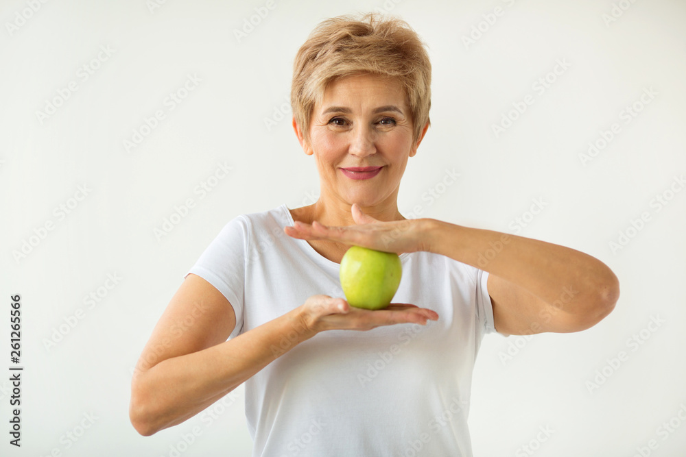 beautiful aged woman with short haircut in a white t-shirt with an apple on a white background beautiful aged woman with short haircut in a white t-shirt with an apple on a white background