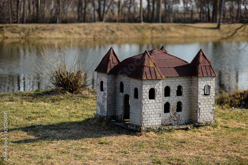 Fototapeta Naklejka Na Ścianę i Meble -  Doghouse in shape of a castle on the river bank in a park