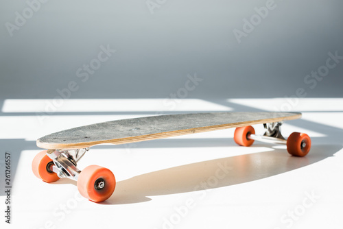 selective focus of longboard in sunlight with shadows on grey