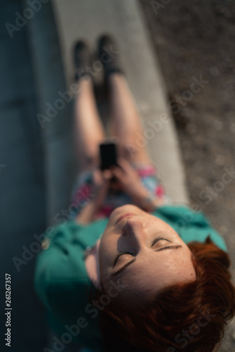 Overview of a young woman uses phone in a palace park sitting on a fountain - View from above