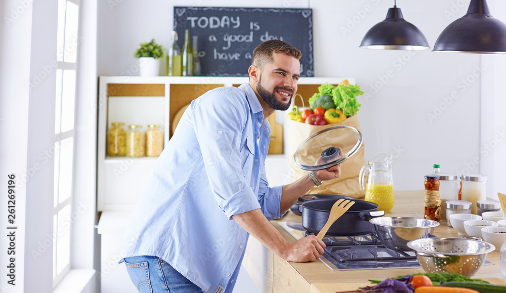 Smiling and confident chef standing in a large kitchen tasting Smiling and confident chef standing in a large kitchen tasting