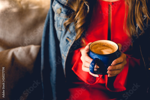 cropped view of young woman holding cup of coffee in cafe