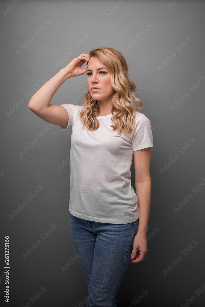 A woman thinks holding her head or has a headache. On a gray background. A woman thinks holding her head or has a headache. On a gray background.