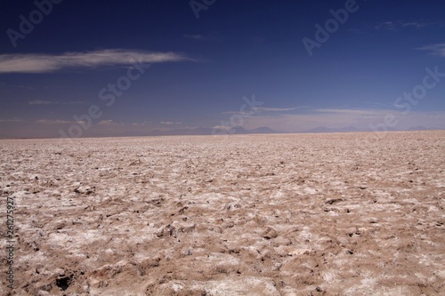 View over endless bright white and brown barren salt plateau into blurred horizon contrasting with deep blue sky - Salar (Salt flat) near San Pedro de Atacama, Chile