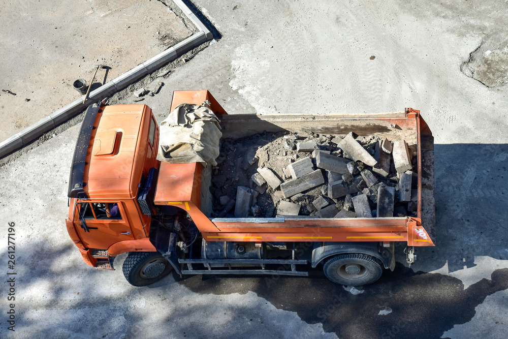 Heavy industrial dump truck .City road construction and renewal site. Dump truck brought in to repair roads and sidewalks, replacing curbs on the roads. Almaty, Kazakhsatn