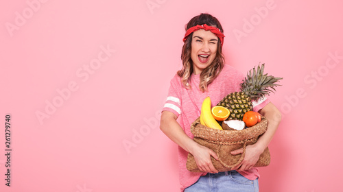 Portrait of a girl with a bag with fruit isolated on a pink background