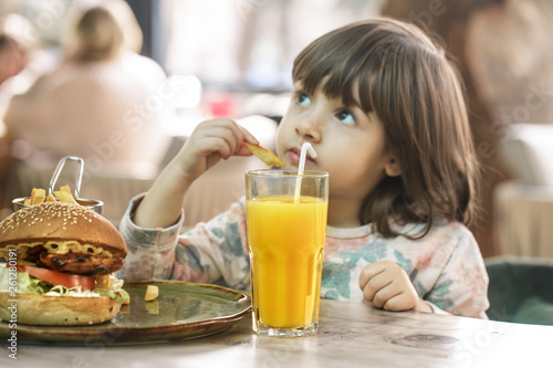 Little girl eats in a fast food cafe