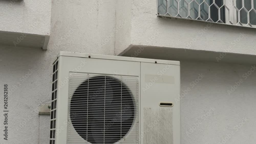 Air conditioner unit outside of the building near apartment windows.