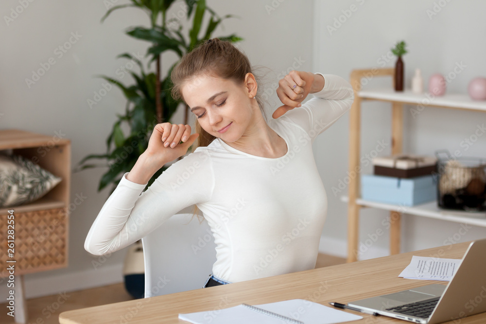 Satisfied young woman stretching, doing exercise at workplace Satisfied young woman stretching, doing exercise at workplace