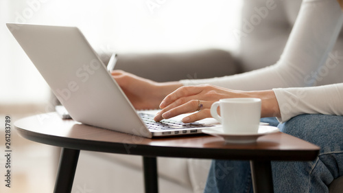 Close up woman using laptop at home, typing, writing notes