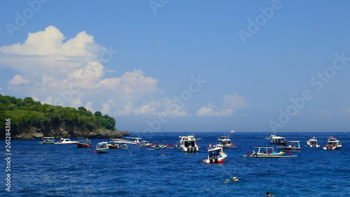 Boote und Badende am Meer unter blauem Himmel in der Crystal Bay in Nusa Penida in Indonesien