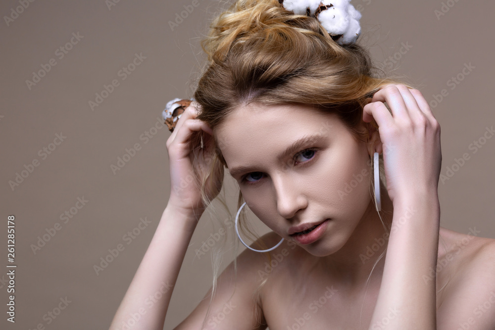 Fototapeta premium Model wearing massive earrings posing near grey background