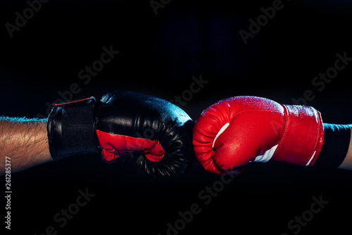 Partial view of two boxers in boxing gloves touching hands on black © LIGHTFIELD STUDIOS