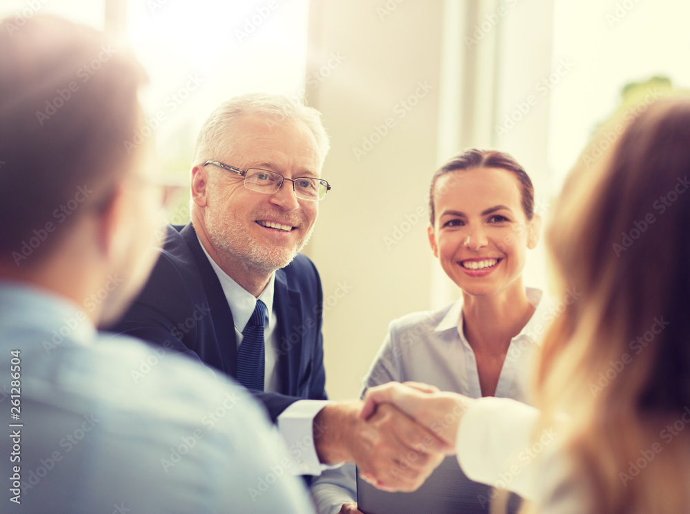 business, people, gesture, cooperation and partnership concept - smiling senior businessman making handshake with woman at office business, people, gesture, cooperation and partnership concept - smiling senior businessman making handshake with woman at office