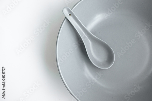 grey color chinese spoon made of ceramics，placed on a light blue plate, isolated in white background