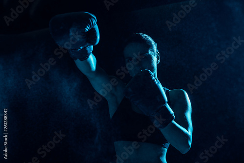 Serious boxer in boxing gloves training and looking away © LIGHTFIELD STUDIOS