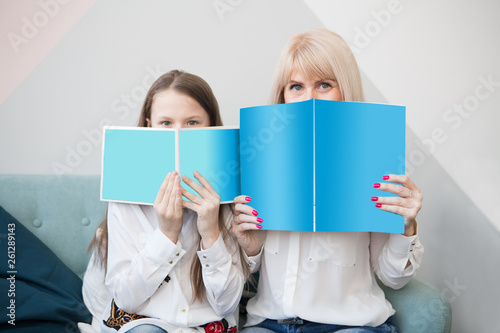 Portrait of cheerfulmother and daughters looking to camerashowing only eyes while hiding face with books.