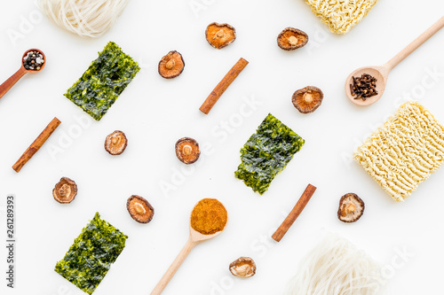 Japanese food cooking with seaweed, spices, pepper, mushrooms and noodles on white background top view geometric pattern
