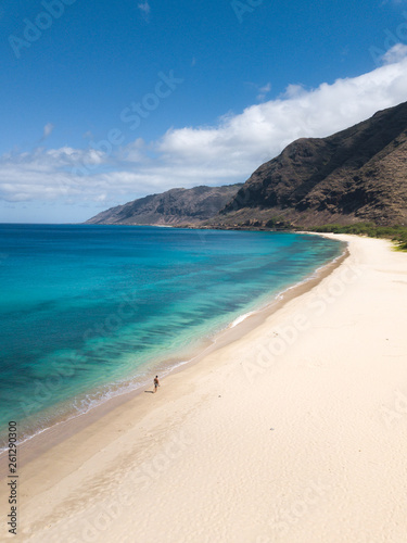 Man walking on the beach - Tropical paradise beach with white sand and mountain background travel tourism wide panorama background. Hawaiian beach. Oahu.