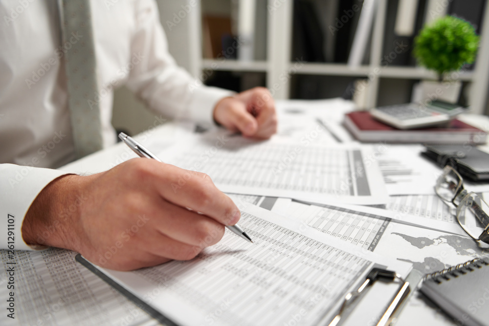 Fototapeta premium Businessman working at office and calculating finance, reads and writes reports. Business financial accounting concept.