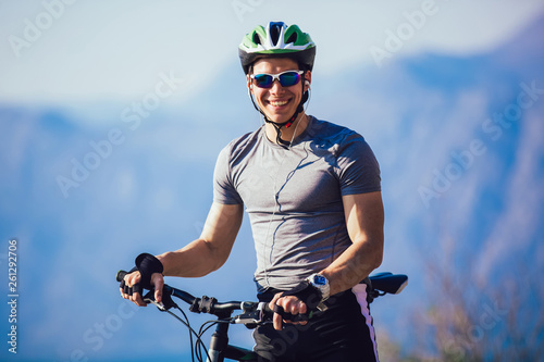 Fototapeta Naklejka Na Ścianę i Meble - Portrait of mountain biker with helmet and sunglasses listening to music and smiling.
