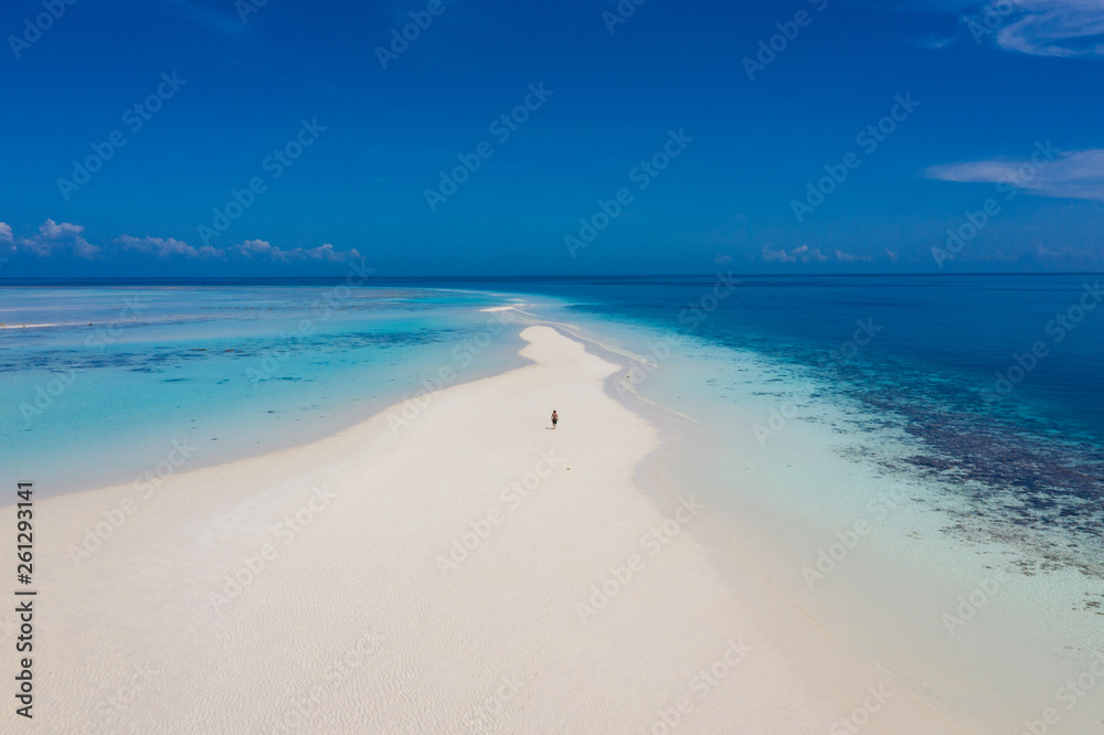 Aerial view of a man walking on the white sand bar in the tropical destination. Hawaii French polynesia Maledives Philippines. Aerial view of a man walking on the white sand bar in the tropical destination. Hawaii French polynesia Maledives Philippines.