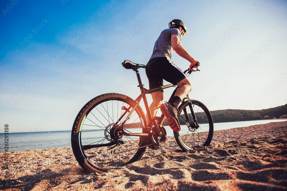 Fototapeta premium Mężczyzna jeździć na rowerze górskim na plaży. Koncepcja sportu i aktywnego życia.